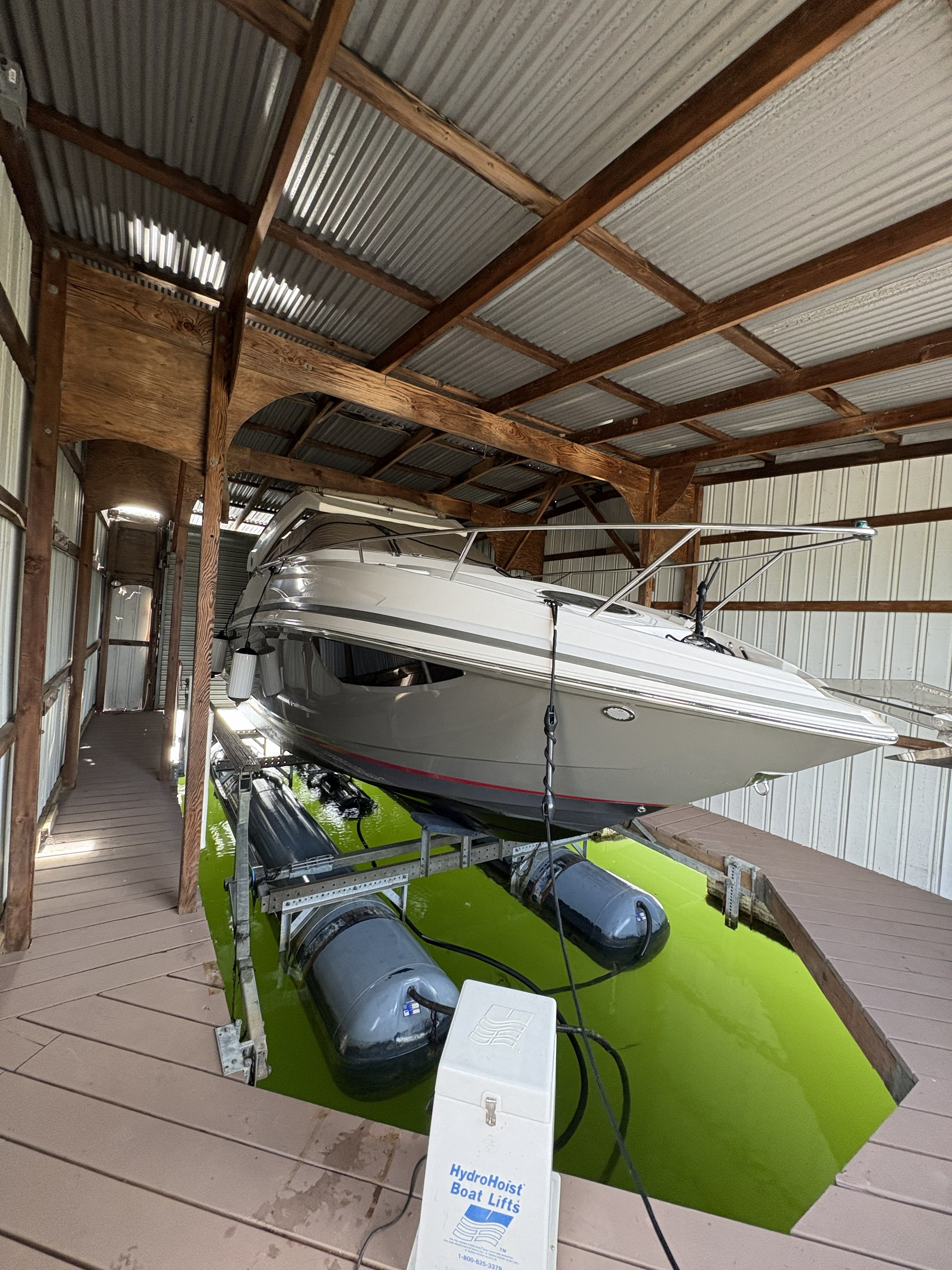 Boat raised on a HydroHoist lift inside a covered slip