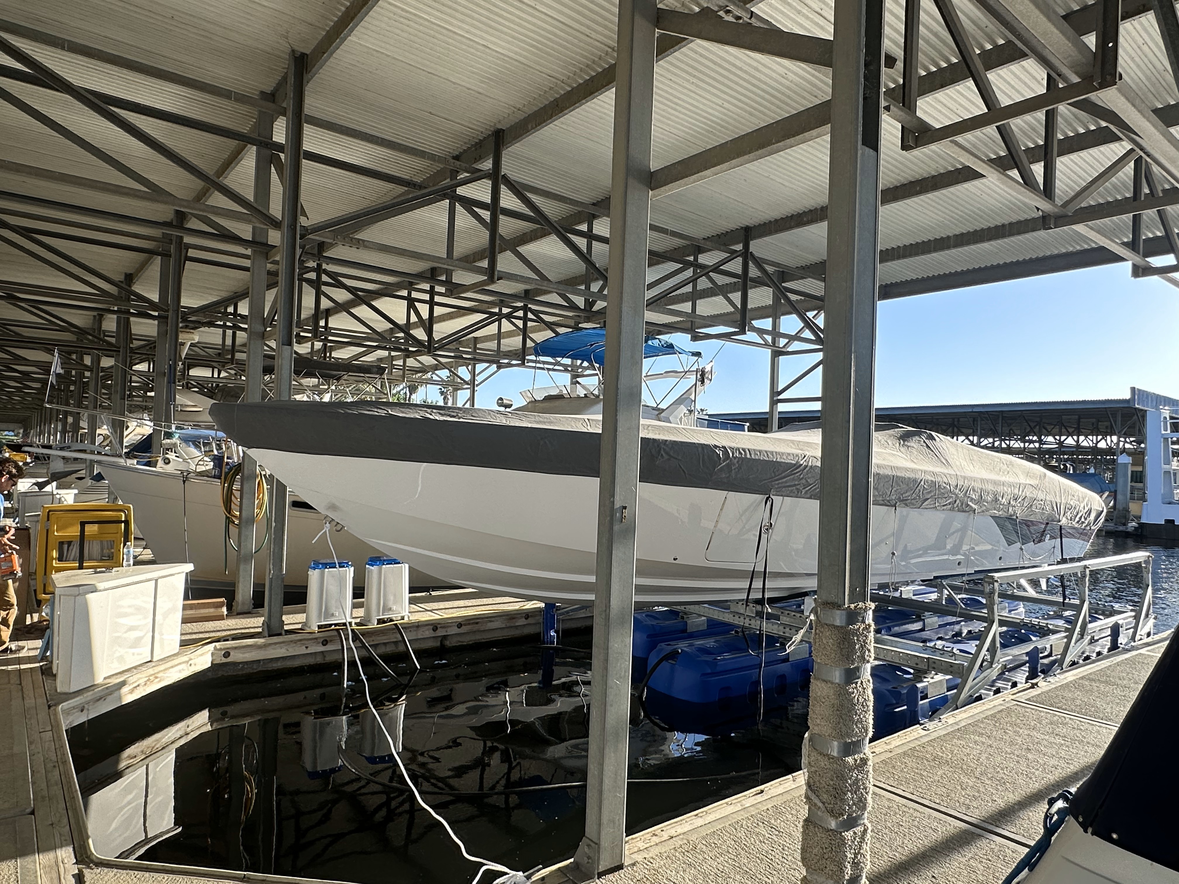 Large performance boat elevated on a custom HydroHoist system in a covered slip