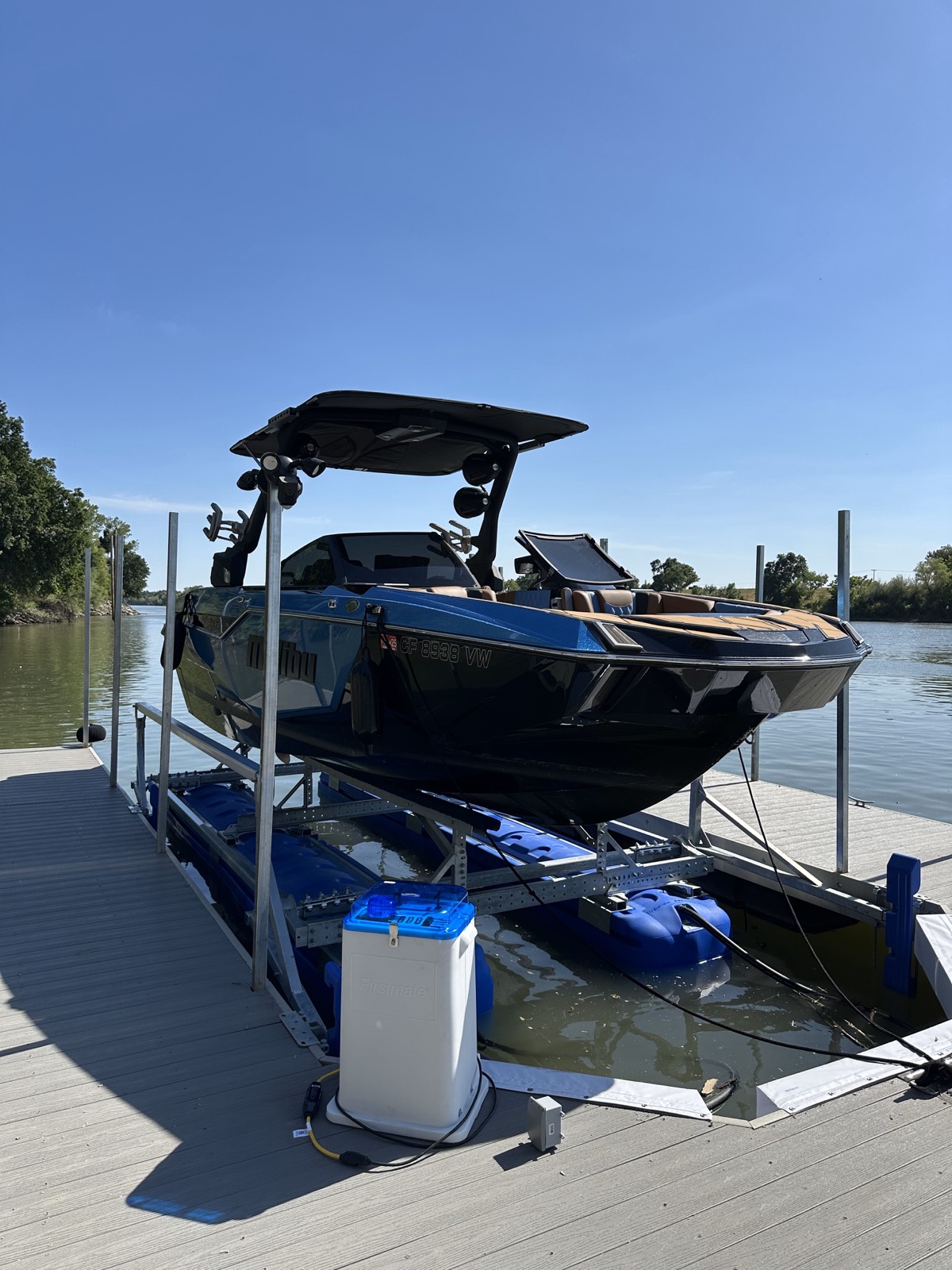 Blue boat supported on a HydroHoist lift beside a waterfront dock